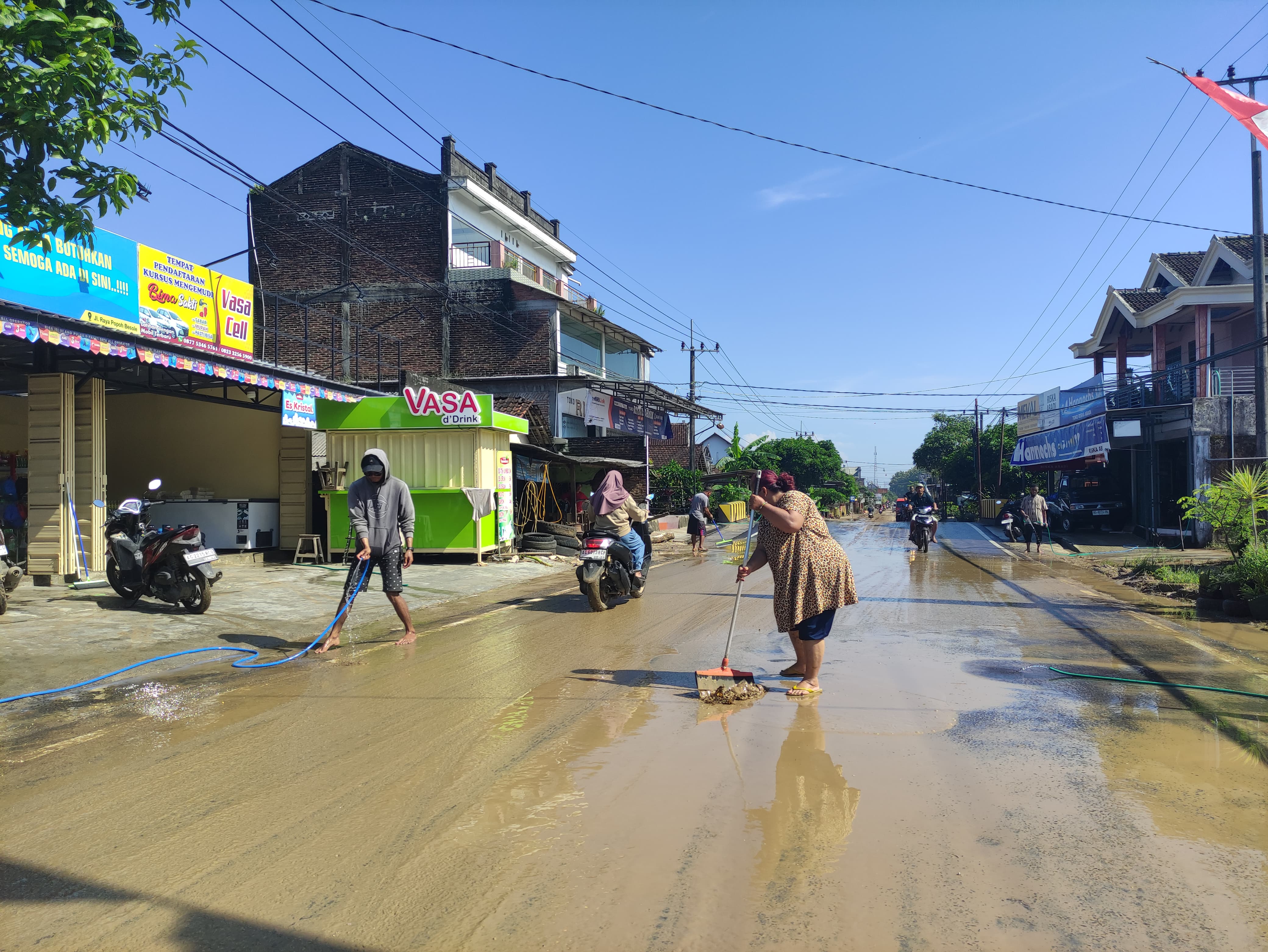 Warga Desa Besole, Tulungagung, bersihkan lumpur di jalan karena luapan air bercampur lumpur akibat hujan deras kemarin (30/1).
