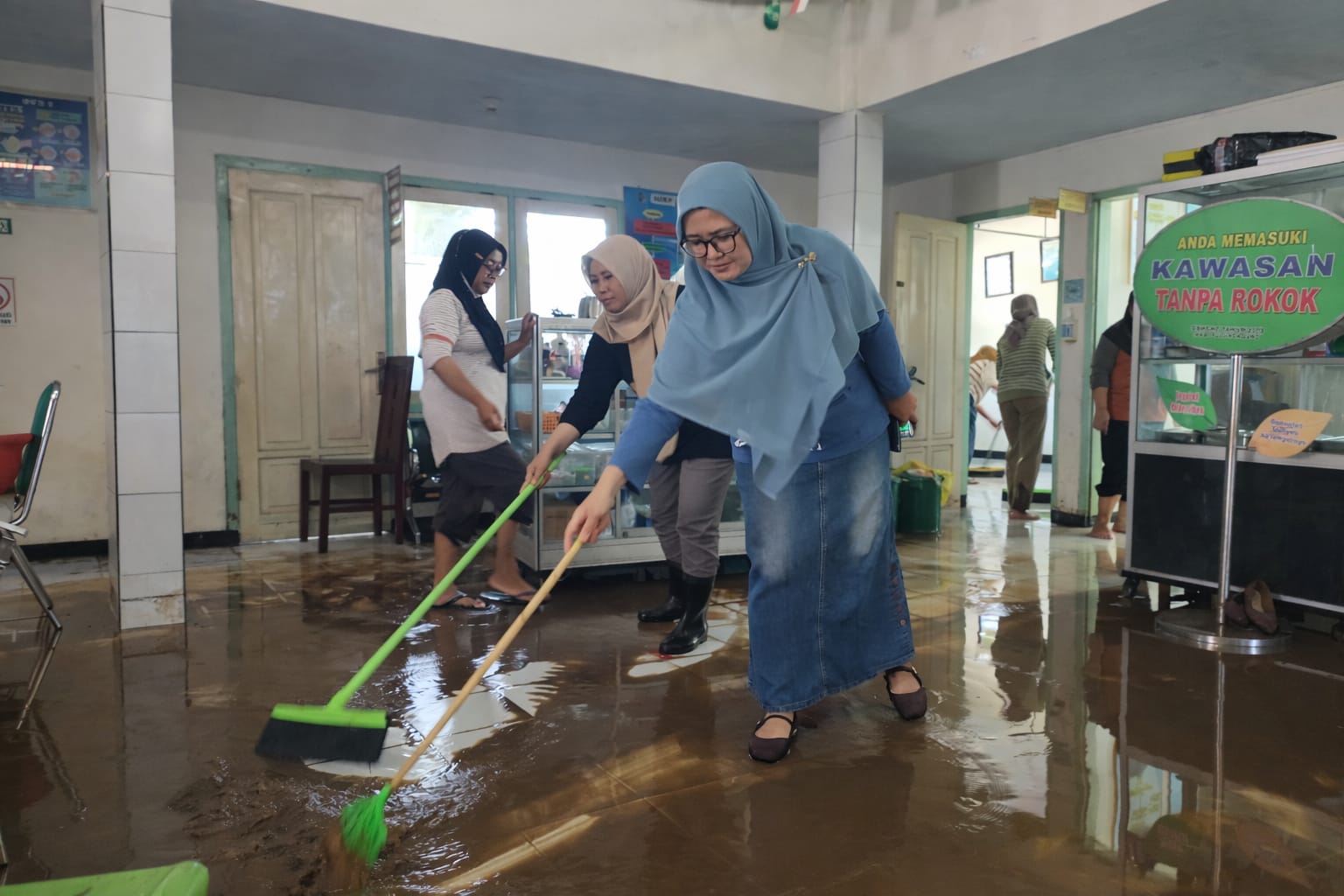 Kepala Dinas Kesehatan Kabupaten Tulungagung, Desi Lusiana Wardhani, ketika ikut membersihkan genangan air dan lumpur di Puskesmas Besole.(SANDY YUWANA/RADAR TULUNGAGUNG)