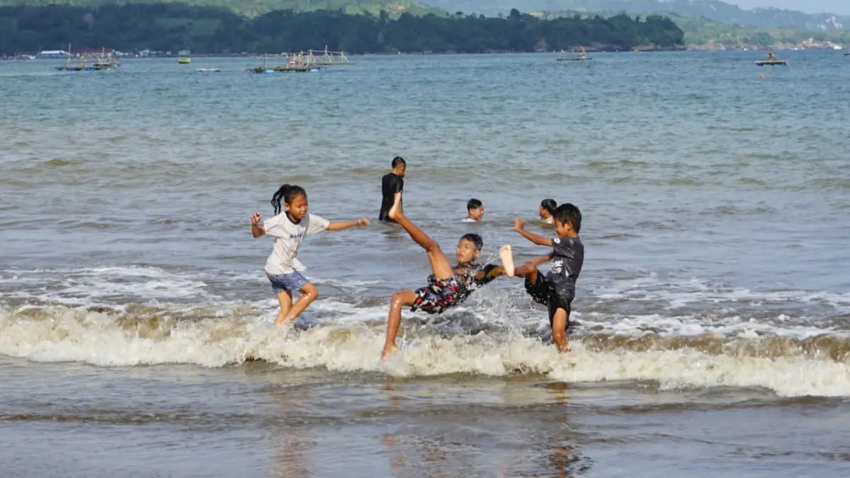 Beberapa wisatawan bocah sedang bermain ombak di kawasan Pantai Gemah, Desa Keboireng, Kecamatan Besuki, Tulungagung, pada Selasa (24/3) kemarin.(DR PERDANA/RADAR TULUNGAGUNG)