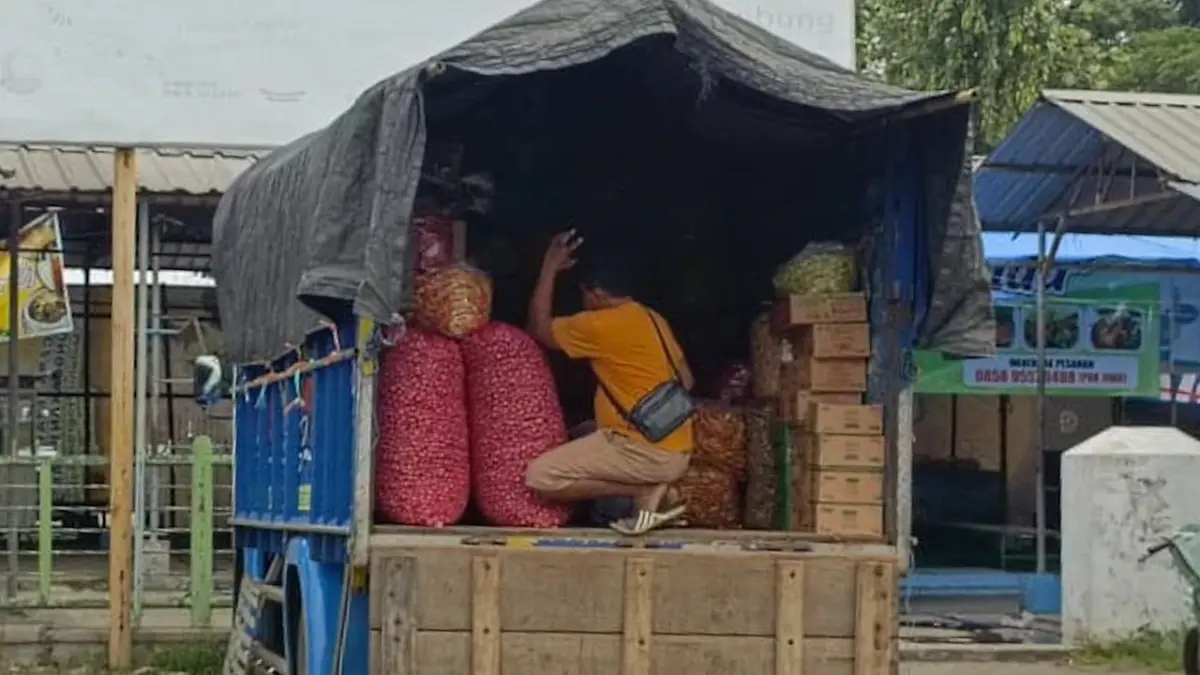 Salah satu pembeli sedang menaikkan bumbu dapur ke atas truk di area parkir Pasar Ngemplak Tulungagung, kemarin (31/3/2026).(RAHIIQ AL BACHRI/RADAR TULUNGAGUNG)