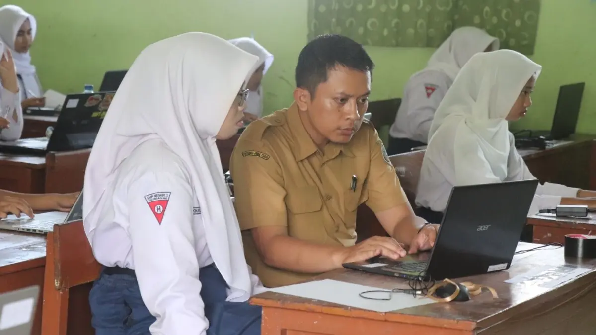 Seorang guru pengawas sedang membantu salah satu siswi SMPN 2 Tulungagung yang terkendala jaringan saat mengerjakan TKA.(SANDY YUWANA/RADAR TULUNGAGUNG)