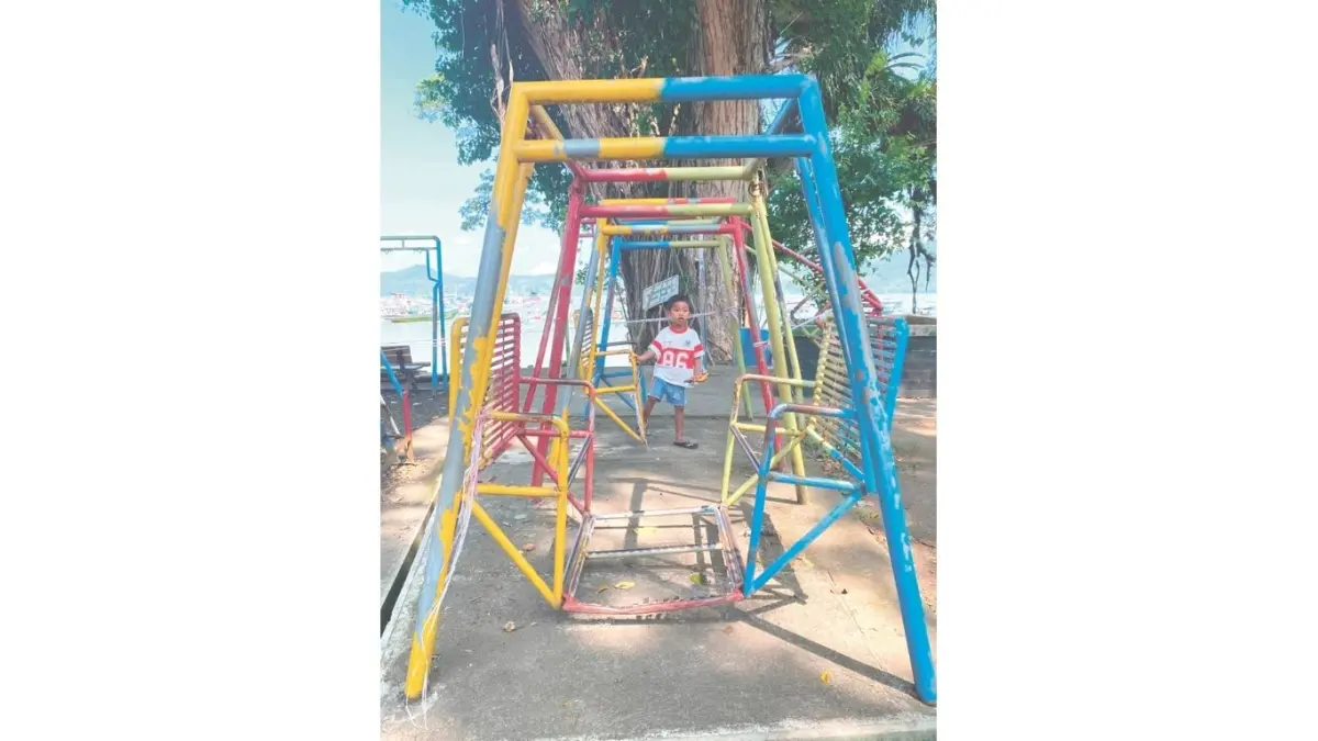 Anak kecil bermain di wahana permainan ayunan Pantai Popoh yang rusak.(DR PERDANA/RADAR TULUNGAGUNG)