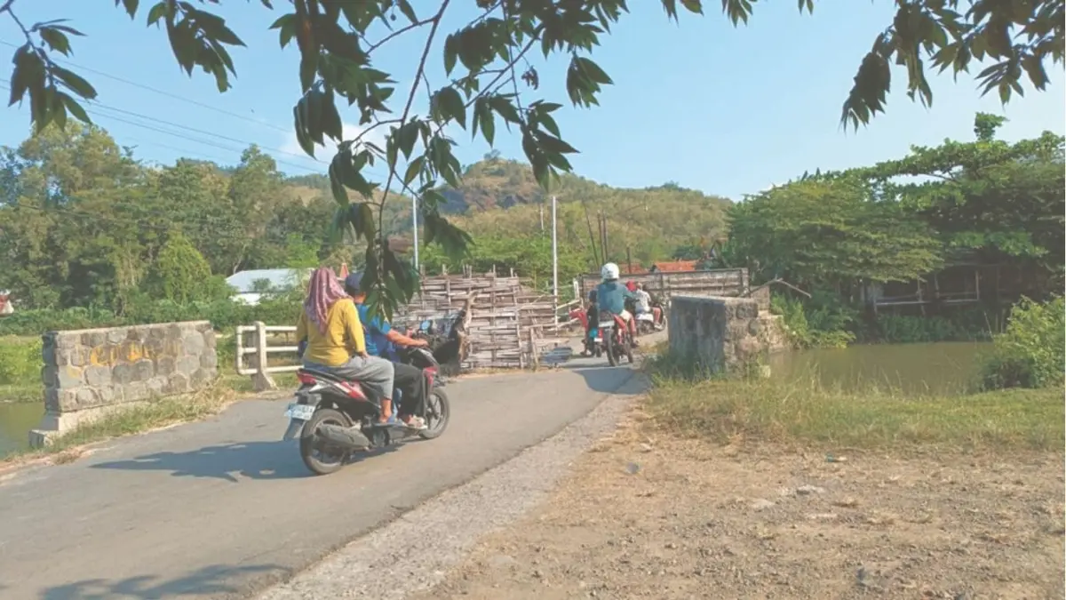 Kendaraan roda dua tetap bebas hilir mudik melintasi Jembatan Junjung yang patah di bagian tengah pada Minggu (10/5/2026).(RAHIIQ AL BACHRI/RADAR TULUNGAGUNG)