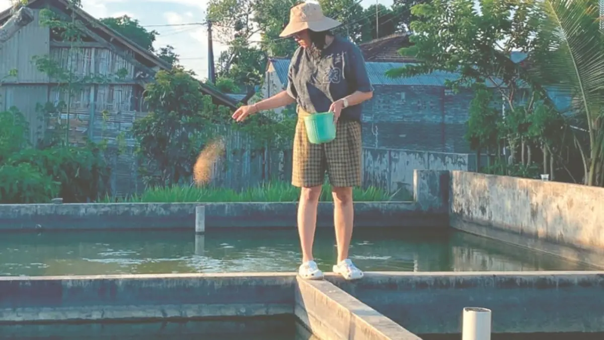 Nita memberi pakan ikan hias yang dibudidayakan di kolam miliknya.(RAHIIQ AL BACHRI/RADAR TULUNGAGUNG)