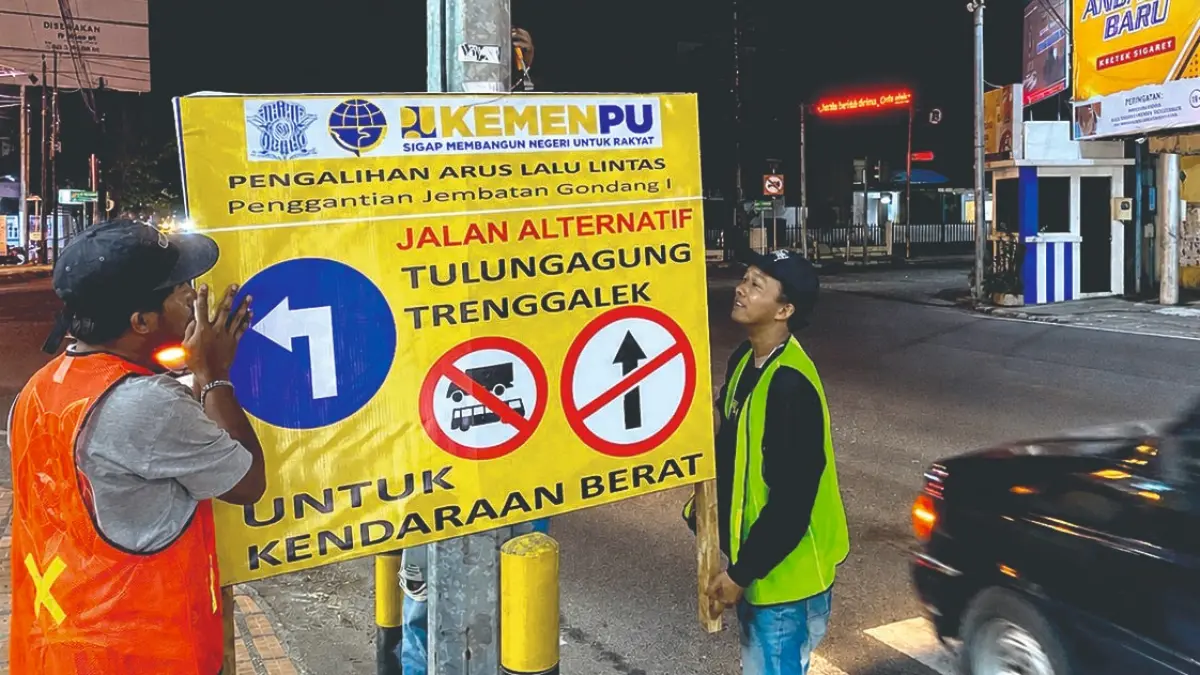 Pekerja BBPJN Jawa Timur-Bali memasang rambu penunjuk jalur alternatif di simpang empat Tamanan pada Senin (25/5/2026) malam.(DR PERDANA/RADAR TULUNGAGUNG)