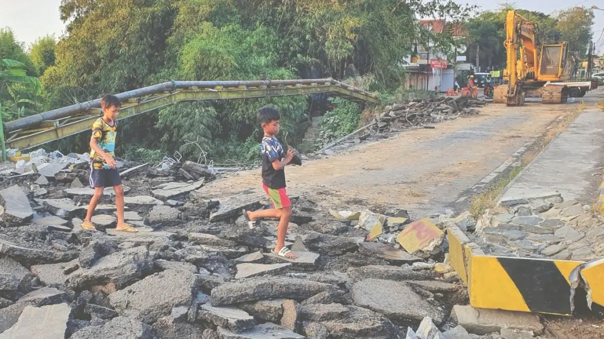 Tampak dua bocah sedang bermain di atas lapisan aspal Jembatan Gondang 1 yang saat ini sedang dibongkar. Penggantian jembatan ini juga berdampak pada rute bus sekolah ke Gondang yang hanya sampai mapolsek setempat.(DR PERDANA/RADAR TULUNGAGUNG)
