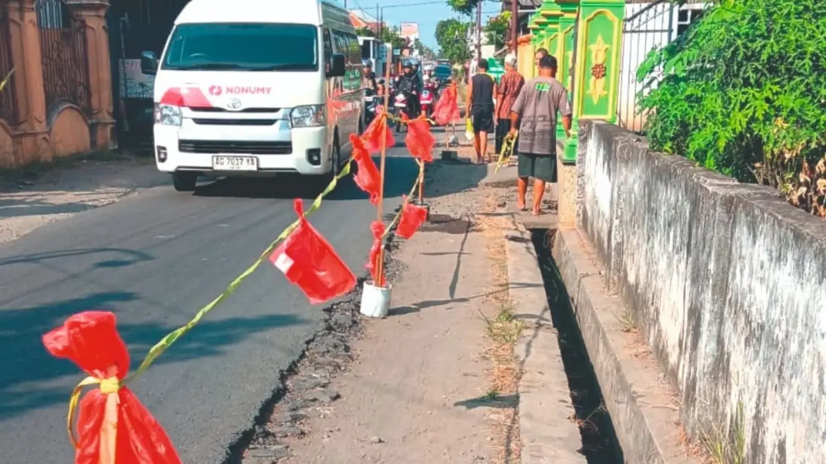 Warga Desa Mojoarum memasang tali di pinggir jalan desa selama pengalihan rute kendaraan akibat penggantian Jembatan Gondang 1 Tulungagung.(RAHIIQ AL BACHRI/RADAR TULUNGAGUNG)
