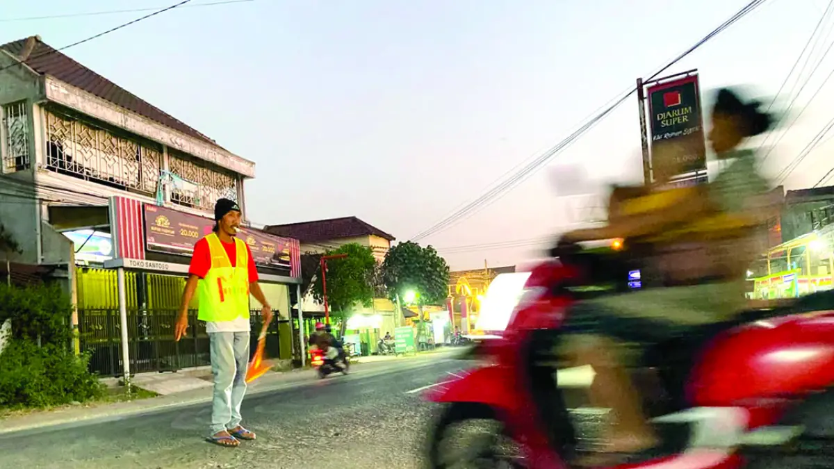 Arif mengatur lalu lintas di persimpangan jalan menuju Desa Mojoarum, Kecamatan Gondang, Tulungagung, pada Minggu (7/6) sore.(DR PERDANA/RADAR TULUNGAGUNG)
