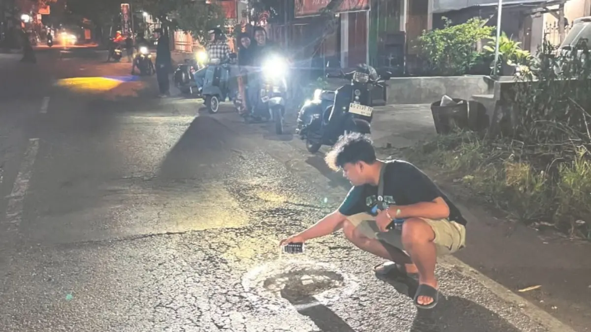 Anggota komunitas skuter Sekutu Tulungagung memberi tanda cat pada jalan berlubang melalui aksi #SAPALONG (Salam Aspal Bolong).(SEKUTU UNTUK RADAR TULUNGAGUNG)