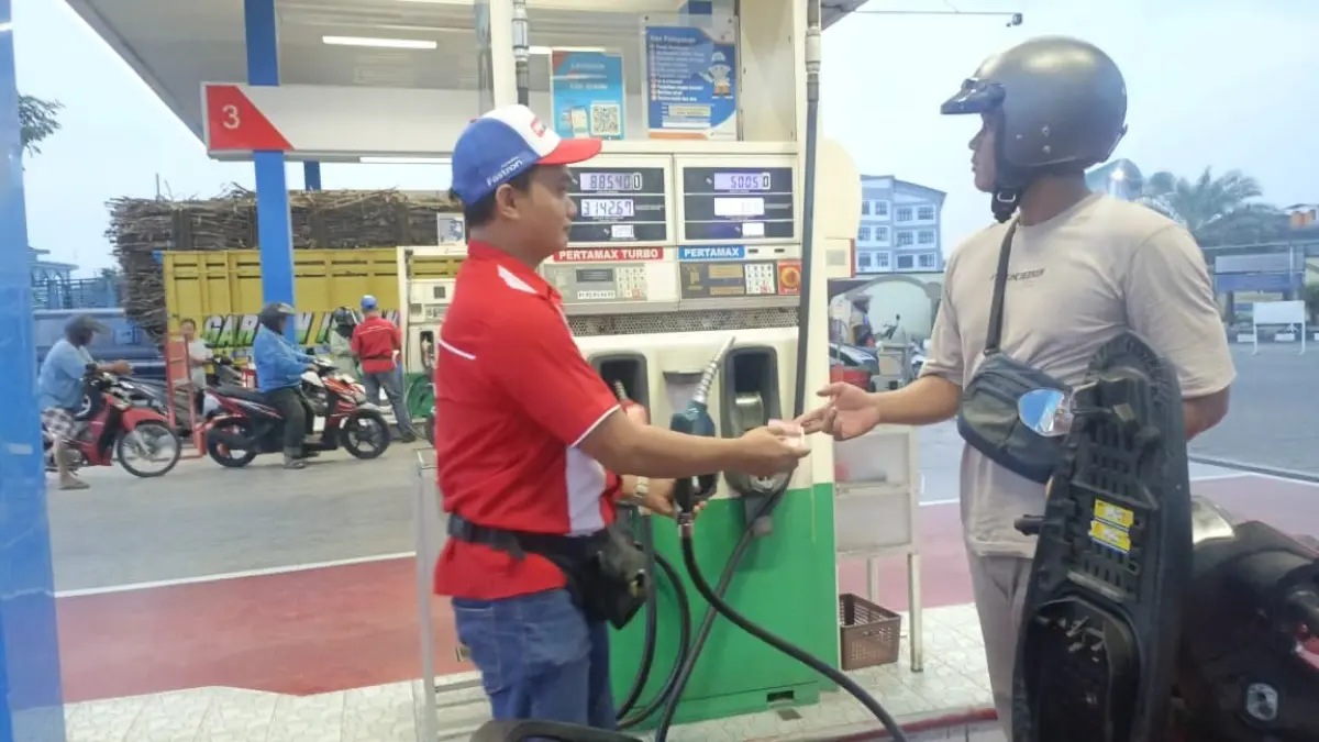 Petugas SPBU Plosokandang Tulungagung sedang melayani pemilik sepeda motor yang membeli BBM.(RAHIIQ/RADAR TULUNGAGUNG)