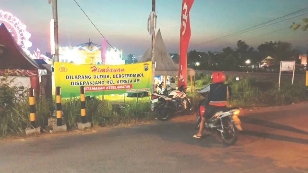 Papan imbauan untuk tidak nongkrong di sekitar rel kereta api yang dipasang Polsek Kedungwaru di Desa Plosokandang, Kecamatan Kedungwaru, Tulungagung.(RAHIIQ AL BACHRI/RADAR TULUNGAGUNG)