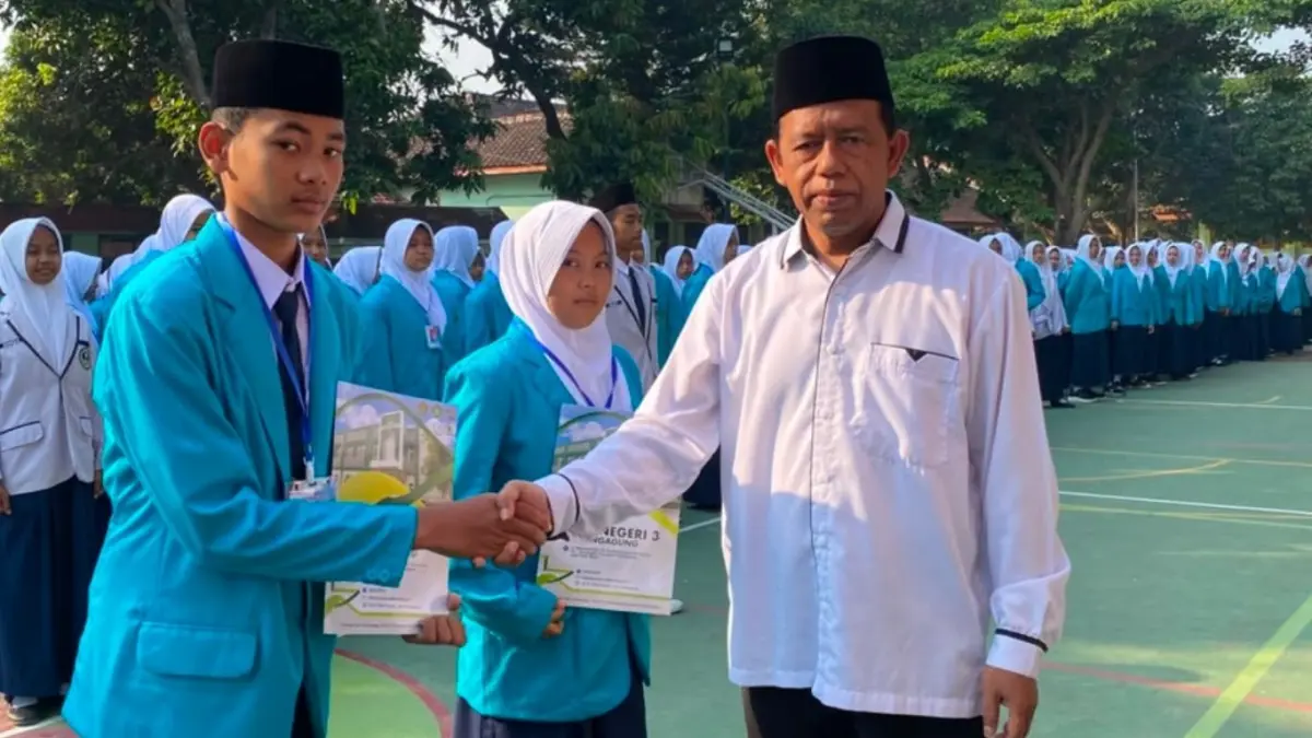 Wakil Kepala MTsN 3 Tulungagung Bidang Kurikulum, Syamsul Arifin SPd, memberikan materi MATAMUDA sekaligus menyerahkan kartu peserta secara simbolis kepada murid baru pada pembukaan Masa Ta’aruf Murid Madrasah (MATAMUDA) tahun ajaran 2026/2027, Senin (13/7).(MATSANEGA UNTUK RADAR TULUNGAGUNG)
