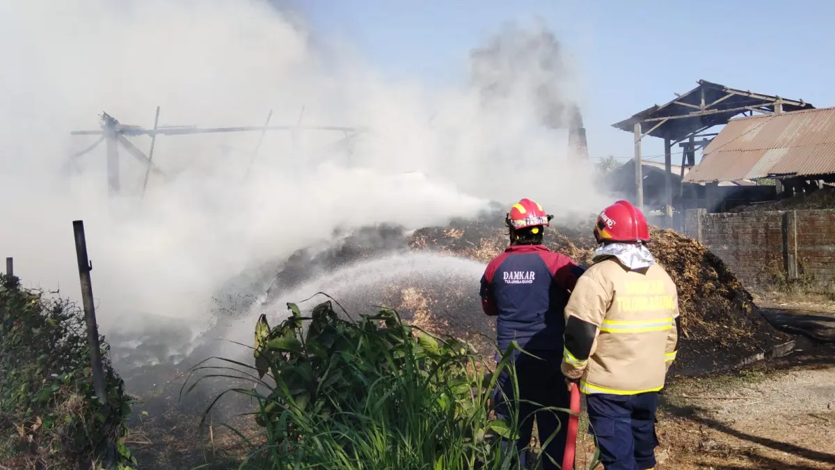 Petugas Damkar Tulungagung berjibaku memadamkan api yang membakar bangunan sepah tebu di area pabrik gula merah Dusun Tapan, Desa Tapan, Kecamatan Kedungwaru, Selasa 25/8. (Damkar Tulungagung)