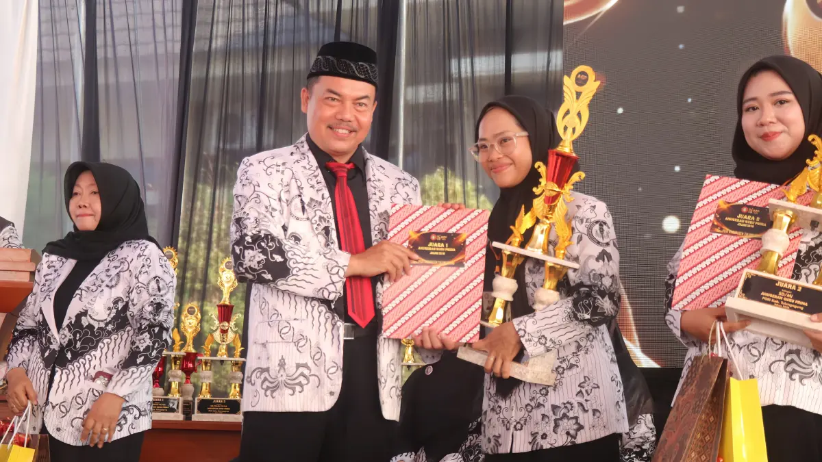 Kandidat perwakilan guru peraih juara 1 jenjang SDN, Nanik Dwi Rahayu SPd, dari SD Negeri 1 Aryojeding Cabang Rejotangan, menerima piala penghargaan langsung dari Ketua PGRI Kabupaten Tulungagung Muhadi SPd MPd, di acara Anugerah Guru Prima 2026 Tulungagung, Rabu (26/8).