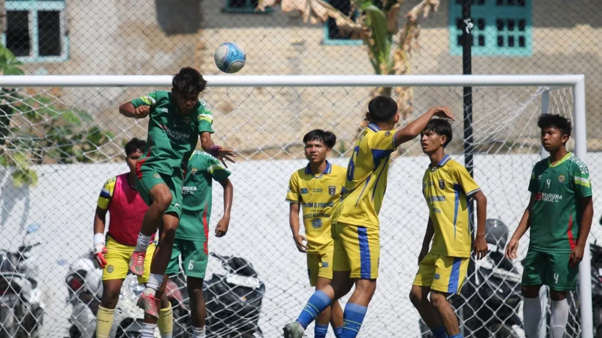 Pemain MAN 2 Pamekasan (jersey hijau) menghalau bola atas saat mendapat serangan dari pemain-pemain SMAN 4 Pamekasan di Turnamen Bahlil Mini Soccer Asyik Menuju Puncak Zona 8 Madura di Puri Dewata Mini Soccer Pamekasan, Jumat (25/9).(FAHMI JALIL/RADAR MADURA)