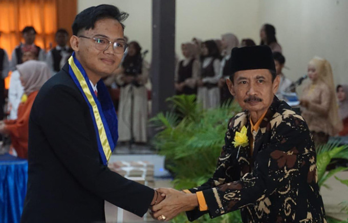 BANGGA: Kepala SMADA Sugeng Riyono bersalaman dan berfoto bersama dengan salah satu wisudawan. (FOTO : BIMA FAISAL/RADAR TRENGGALEK)