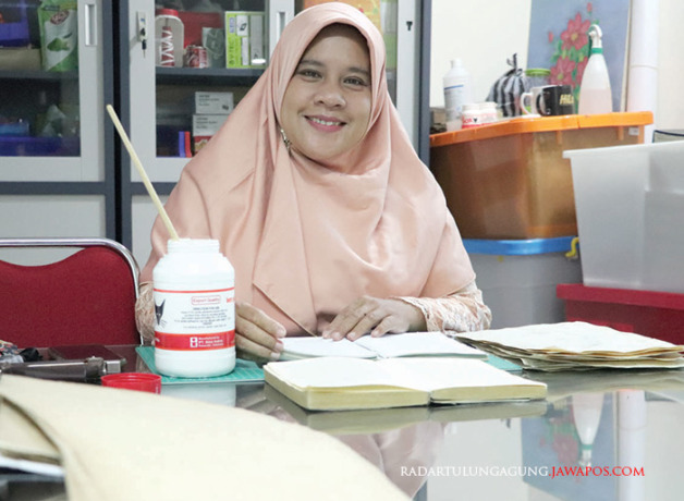 TELITI: Rosalia sedang memperbaiki buku saat ditemui di ruang kerjanya kemarin (17/5). (AGUS MUHAIMIN/ RADAR BLITAR)