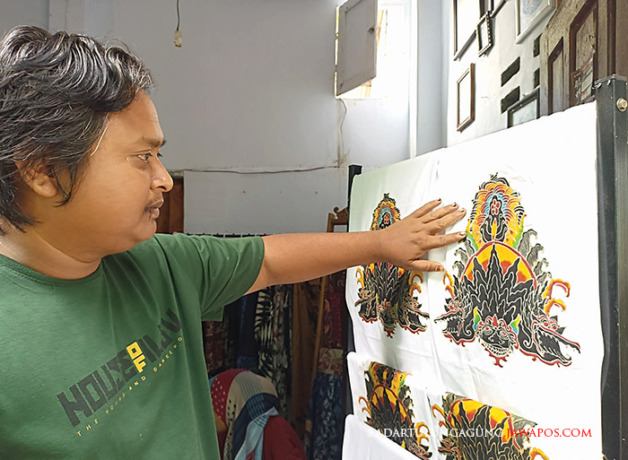 ANGKAT SENI DAERAH: Micky saat mengerjakan desain batik motif barongan kucingan di galeri sederhananya di Kelurahan Turi, Kecamatan Sukorejo, beberapa waktu lalu. (MOCHAMMAD SUBCHAN ABDULLAH/RADAR BLITAR)