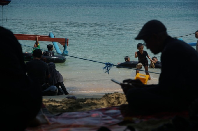 TERHUBUNG: Masyarakat ketika mengakses internet menggunakan smartphone di daerah wisata Pantai Karanggongso, Kecamatan Watulimo, yang sudah terjangkau internet. (foto: DR Perdana)