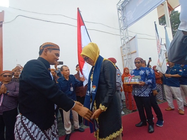 ESTAFET: Ketua KPU Kabupaten Blitar Hadi Santosa menyambut Ketua KPU Kabupaten Malang, Anis Suhartini dan rombongannya, yang membawa bendera Kirab Pemilu 2024. (MOCHAMMAD LUKI AZHARI/RADAR BLITAR)