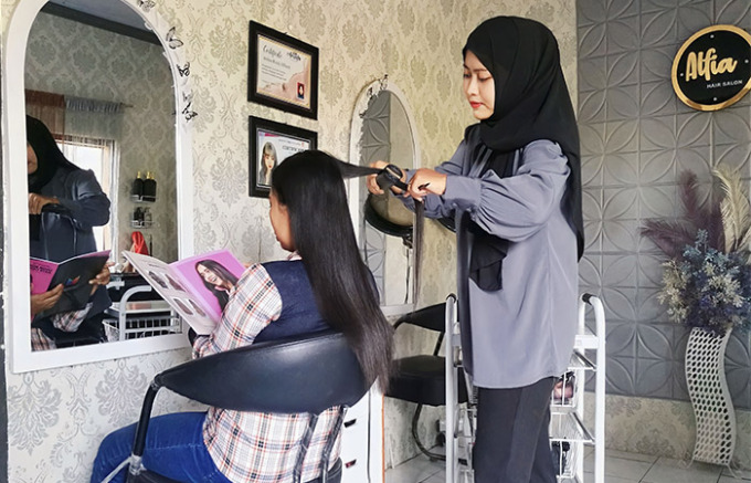 Ramah : Owner Alfia salon Anisa Rizqi Alfiani juga terjun langsung melayani pelanggan melakukan potong rambut. (Foto : NANIK HIDAYAH / RADAR TULUNGAGUNG)