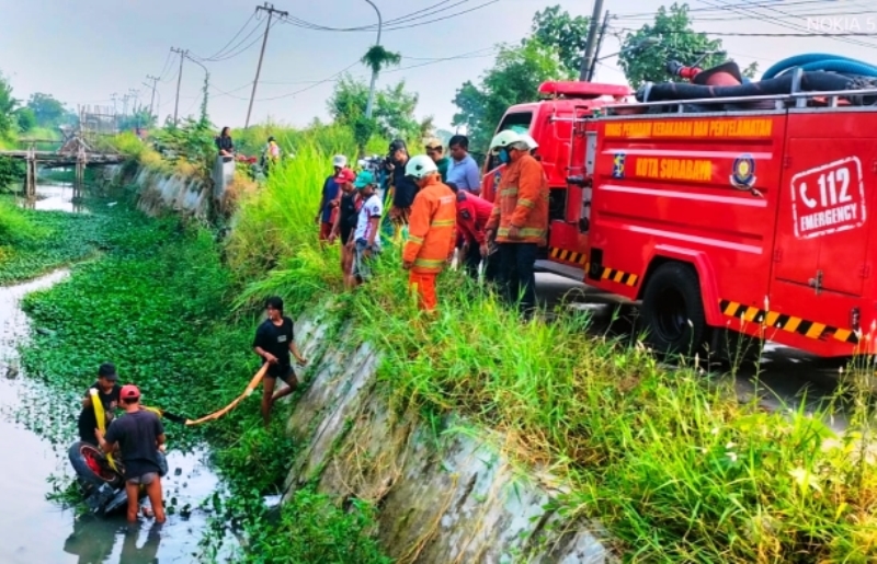 DIANGKAT: Petugas DPKP mengevakuasi motor yang tercebur di sungai Jalan Tambak Dono. (ISTIMEWA)