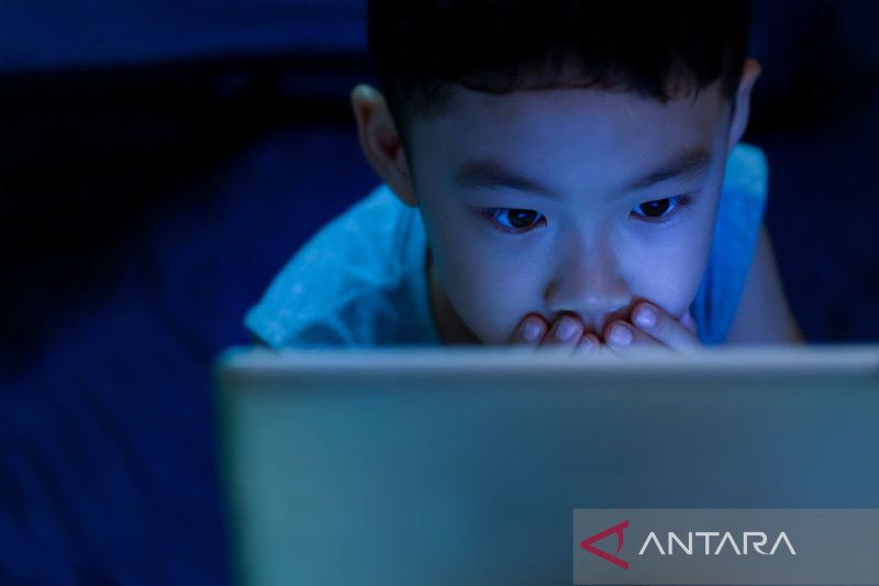 Ilustrasi - Anak kecil menggunakan 2 tangan menutup mulutnya saat melihat konten kekerasan atau sensitif di tablet dengan cahaya redup gelap. ANTARA/Shutterstock/pri. (ANTARA/Shutterstock)