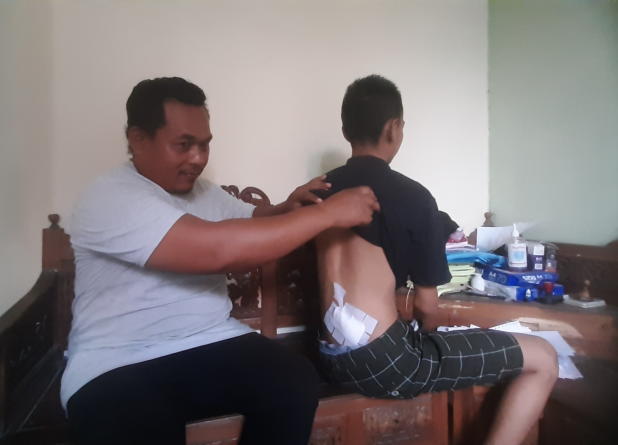 DIPERBAN: Wadi Anggara menunjukkan punggung anaknya, RD, yang luka terkena bacokan. (MAHRUS/RADAR SURABAYA)