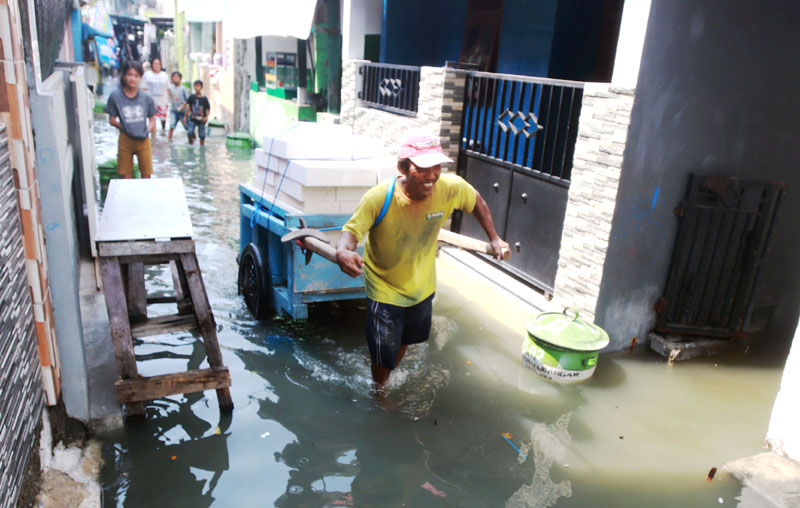TERGENANG: Warga melewati genangan air yang membanjiri lingkungan temnpat tinggal mereka di Jalan Kalianak, Surabaya, Rabu (5/7). (ANDY SATRIA/RADAR SURABAYA)
