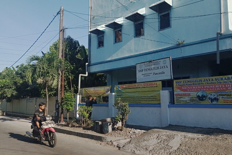 SEPI PEMINAT: Pengendara kendaraan bermotor melintas tak jauh dari bangunan SMP Tenggilis Jaya Surabaya, Selasa (18/7). (SURYANTO/RADAR SURABAYA)