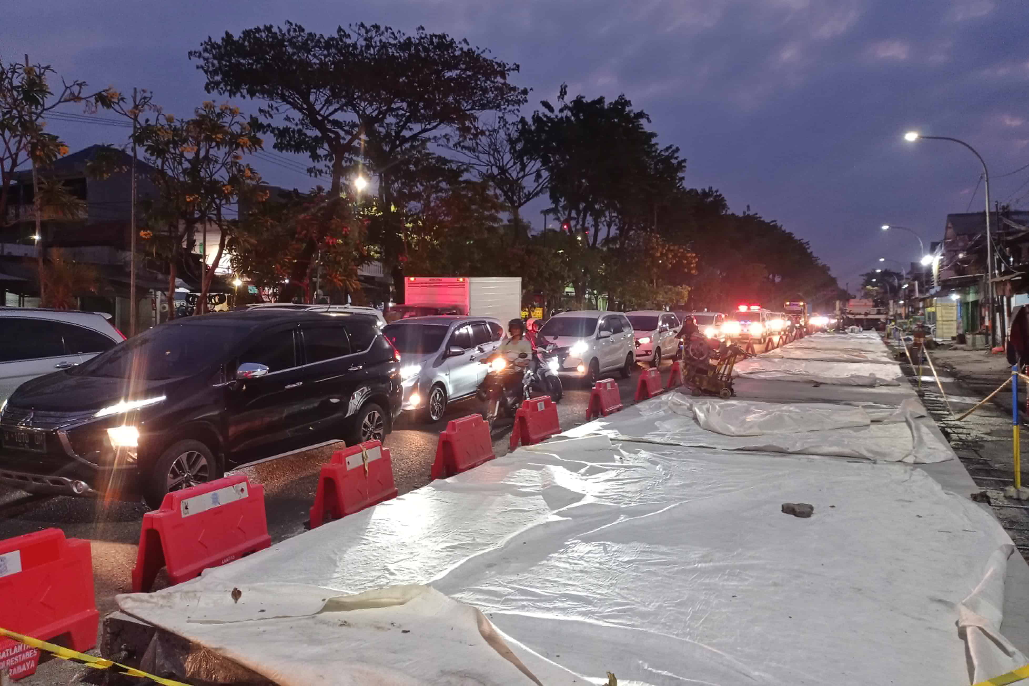 PADAT: Pengendara kendaraan bermotor melintas tak jauh dari proyek betonisasi di Jalan Dupak, Selasa (25/7). (SURYANTO/RADAR SURABAYA)