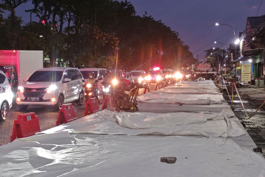 DIMULAI: Pengendara kendaraan bermotor melintas tak jauh dari proyek betonisasi di Jalan Dupak, Surabaya, Selasa (25/7). (SURYANTO/RADAR SURABAYA)