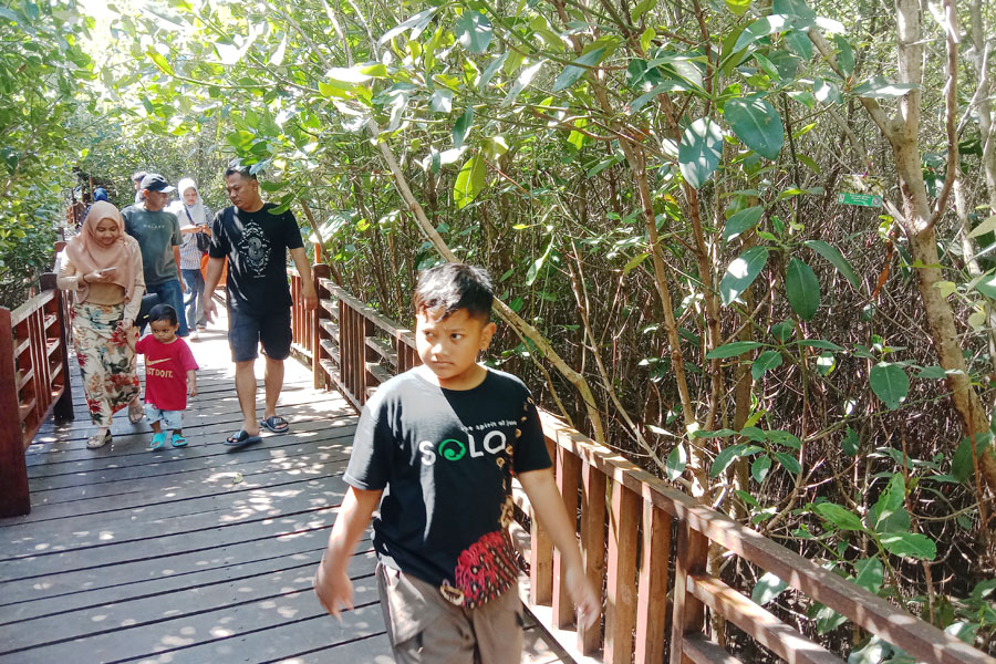 WISATA KELUARGA: Sejumlah warga dari luar kota menikmati suasana Kebun Raya Mangrove (KRM) Surabaya di kawasan Gunung Anyar Surabaya, Minggu (30/7). (SURYANTO/RADAR SURABAYA)