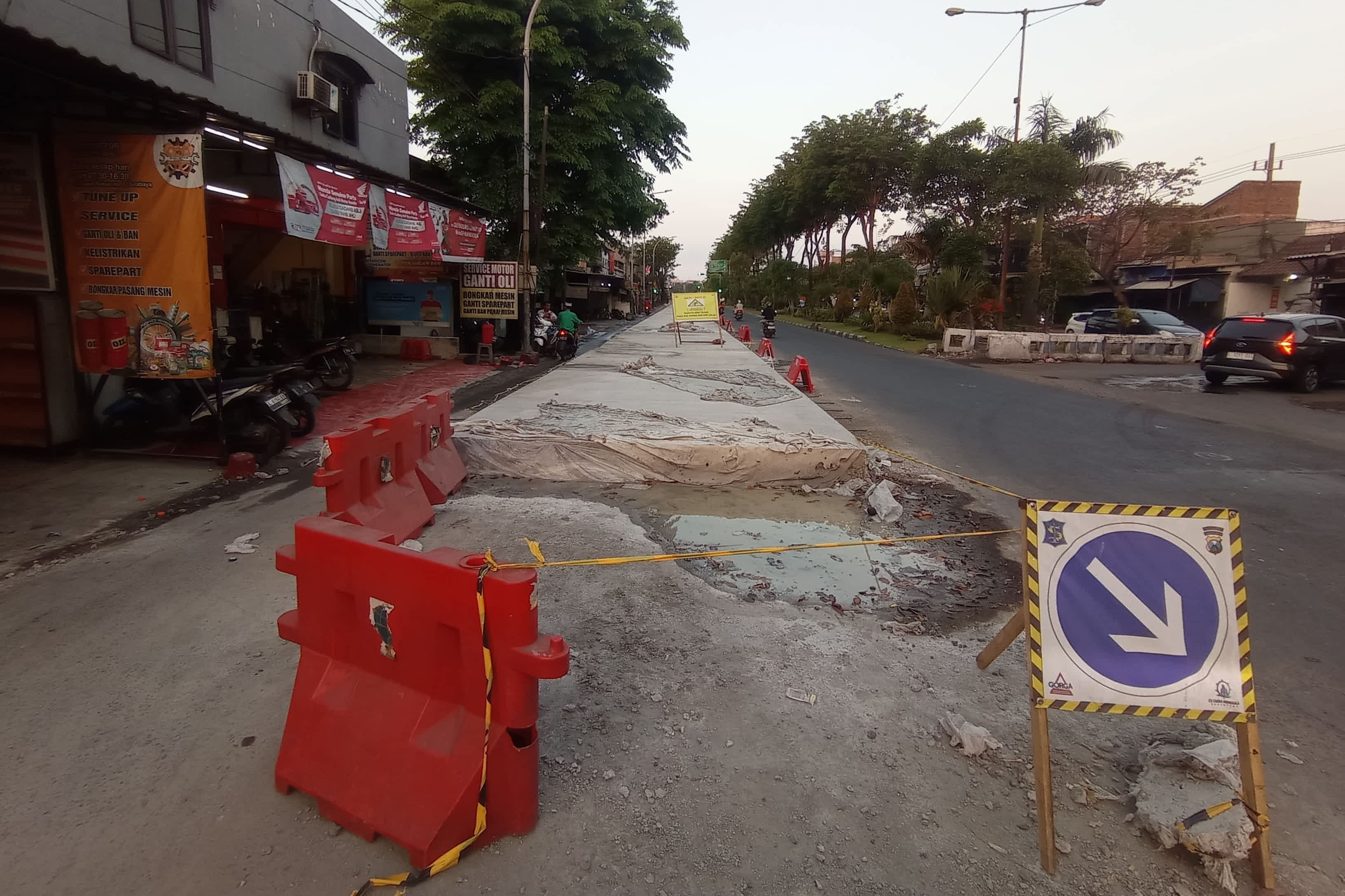 LEBIH KUAT: Pengendara kendaraan bermotor melintas tak jauh dari proyek betonisasi di Jalan Dupak, Surabaya, Minggu (30/7).