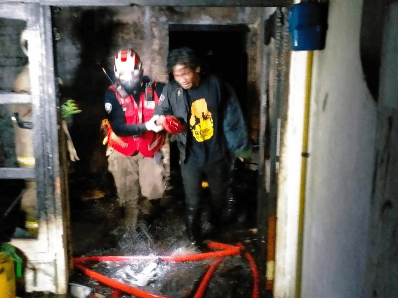 EVAKUASI: Petugas mengevakuasi salah seorang penghuni rumah yang terbakar di Jalan Gresikan I, Surabaya, Selasa (8/8). (ISTIMEWA)