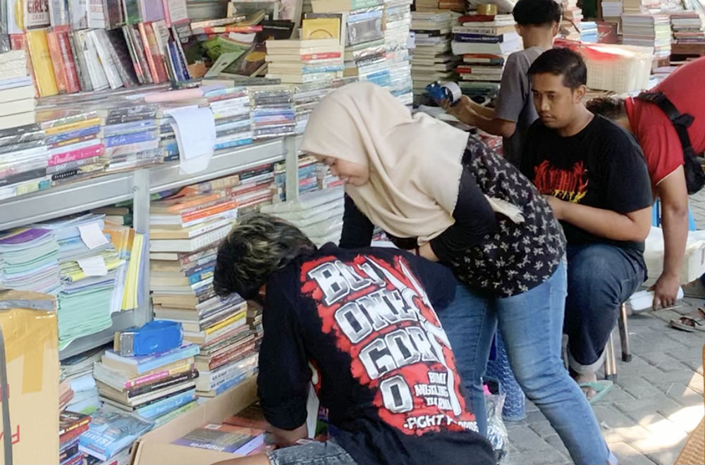 PACKING: Pedagang buku Kampung Ilmu di Jalan Semarang sedang mengemas buku untuk melayani penjualan via online. (INDHIRA AYU/RADAR SURABAYA)
