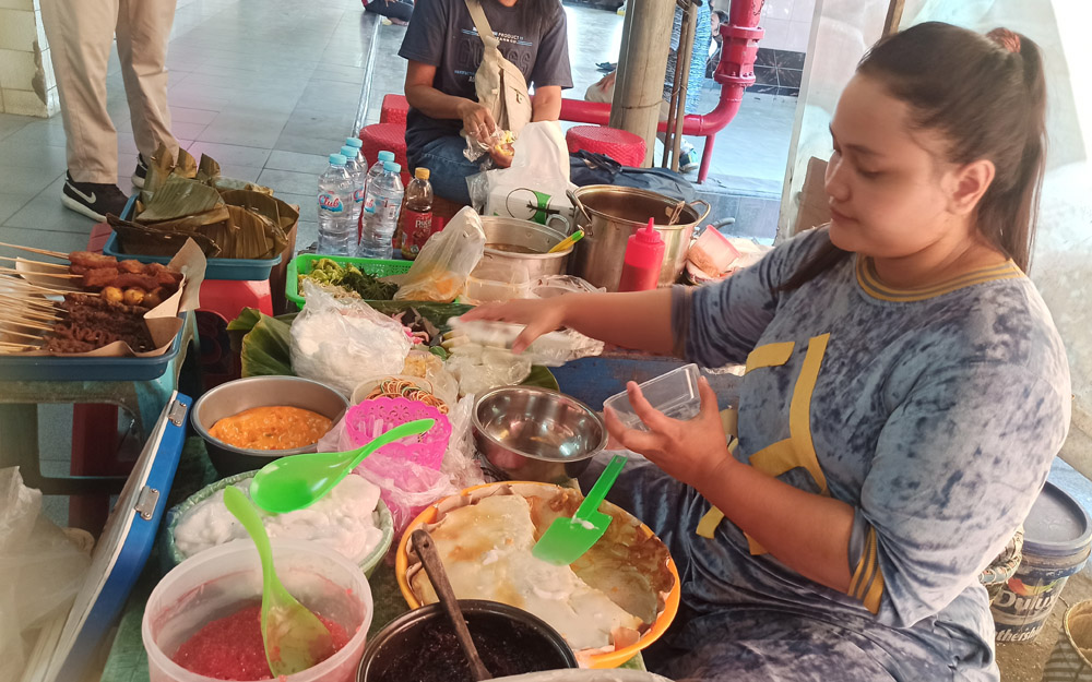Salah satu pedagang Bubur Madura di Pasar Atom, Rosidah, sedang menyiapkan pesanan pelanggan. (ANGELICA/RADAR SURABAYA)