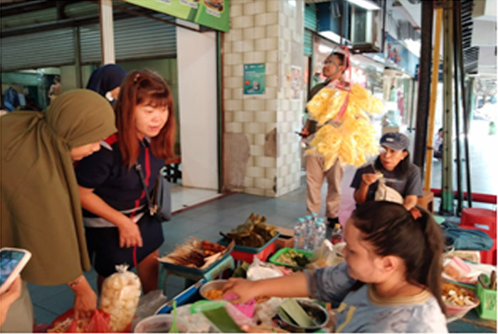 Pembeli yang menikmati Bubur Madura di emperan Pasar Atom lama lantai dasar. (FITROTUL KHUSNUL HIDAYAH/RADAR SURABAYA)