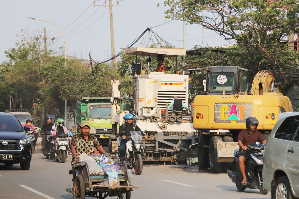 ON TRAGET: Pengendara kendaraan bermotor melintas tak jauh dari proyek betonisasi di Jalan Dupak, Surabaya, Rabu (20/9). (SURYANTO/RADAR SURABAYA)