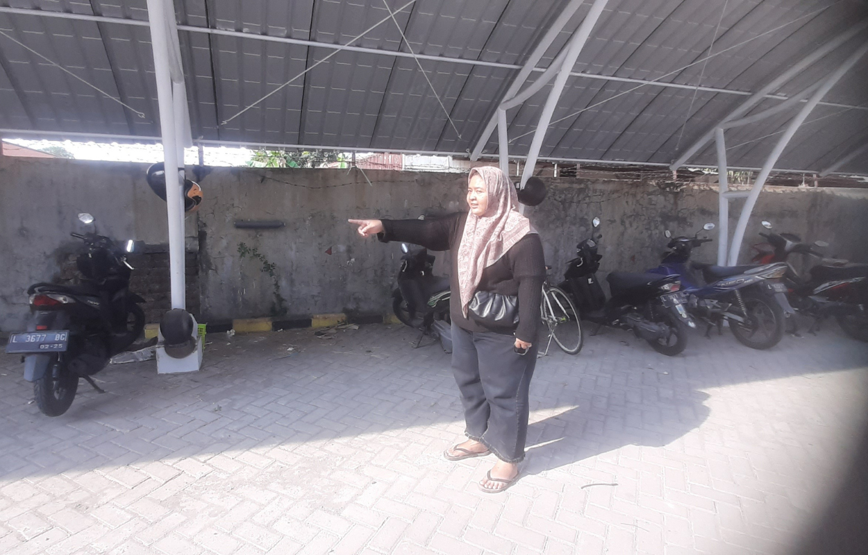 KORBAN: Suci Wahyuningsih menunjukkan lokasi parkir motor di sisi utara Rusunawa Dukuh Menanggal. (MAHRUS/RADAR SURABAYA)