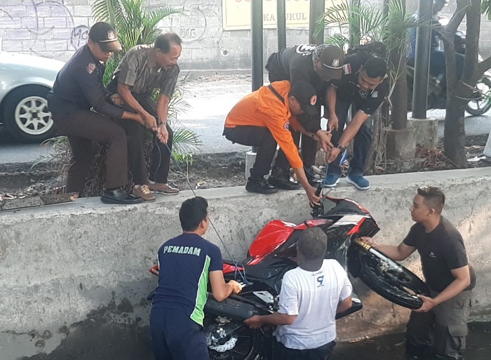 EVAKUASI: Petugas mengevakuasi motor Honda CBR yang terjun ke sungai di Jalan Gayung Kebonsari, Surabaya, Jumat (20/10). (IST)