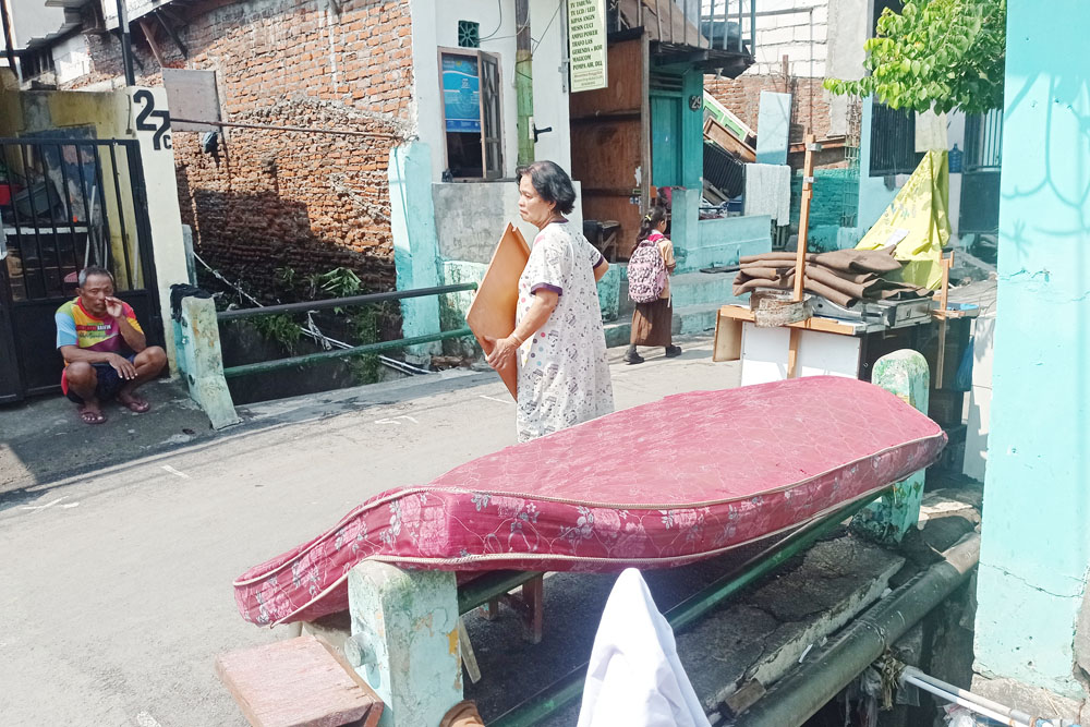 EFEK BANJIR: Warga menjemur barang-barang yang basah akibat banjir di Banyuurip Kidul, Surabaya.