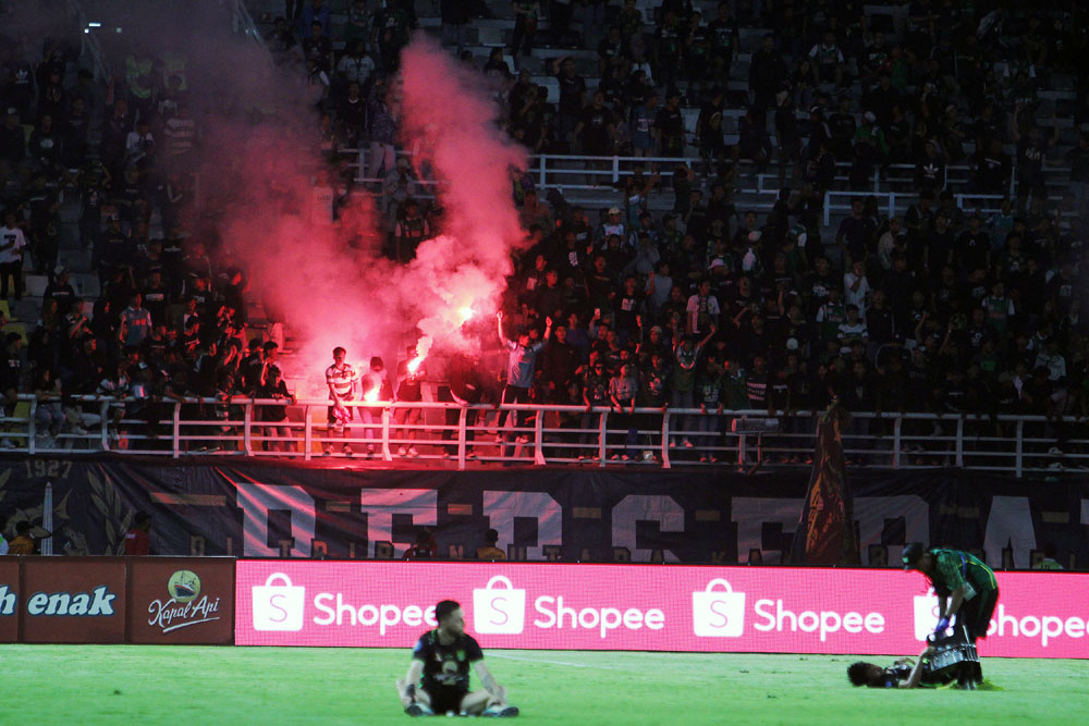 Bonek menyalakan flare di akhir pertandingan usai Persebaya diimbangi Persis Solo 1-1 di Stadion GBT Surabaya, Rabu malam (13/12).