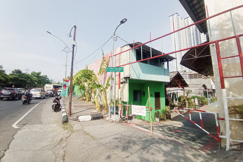 BAKAL DIBEBASKAN: Pengendara melintas tak jauh dari permukiman yang terimbas pembangunan underpass Taman Pelangi, Surabaya.