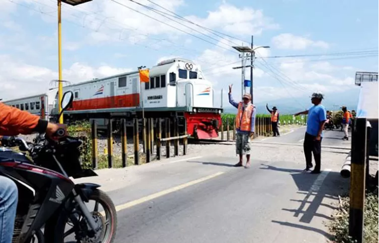 JAGA: Perlintasan KA tanpa palang pintu di Desa Bangle, Kecamatan Ngadiluwih, Kediri, dijaga oleh sukarelawan. (DOK JPC/RADAR KEDIRI)