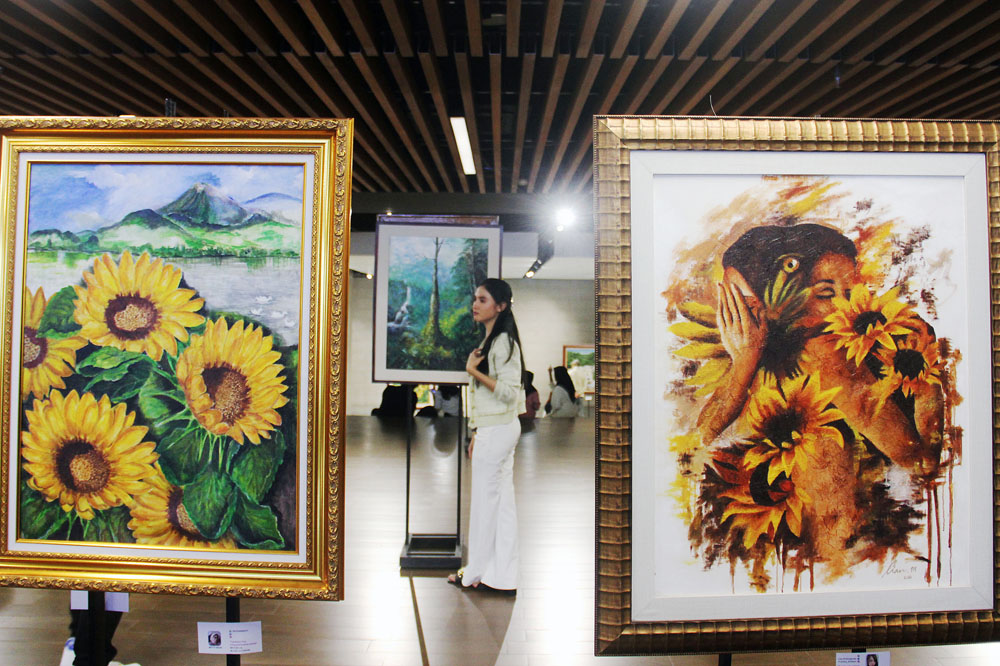 ARTISTIK: Pengunjung mengamati lukisan karya para perupa perempuan yang dipamerkan di basement alun-alun Surabaya, Selasa (26/12).