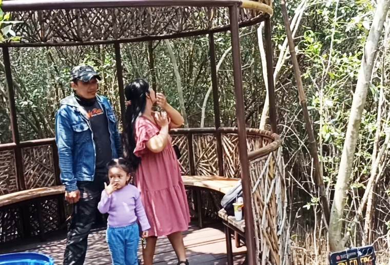 Sebuah keluarga sedang menikmati liburan di Kebun Raya Mangrove Surabaya.