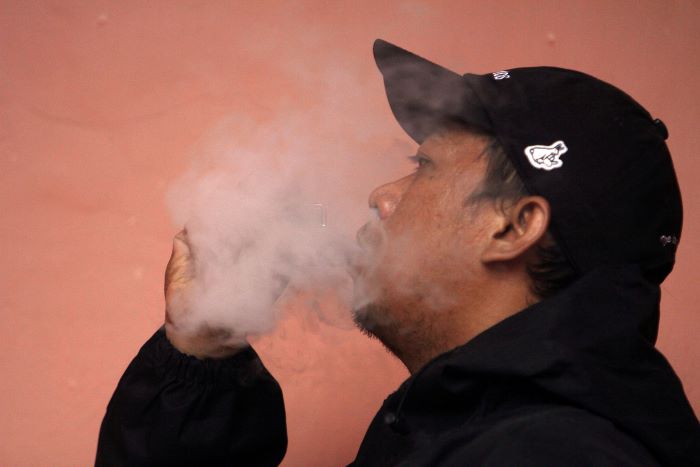 MENIKMATI: Pengguna rokok elektrik, Nyoman Deni, menikmati rasa yang ditimbulkan dari cairan melalui rokok elektrik, di Surabaya, Selasa (9/1). (ANDY S/RADAR SURABAYA)