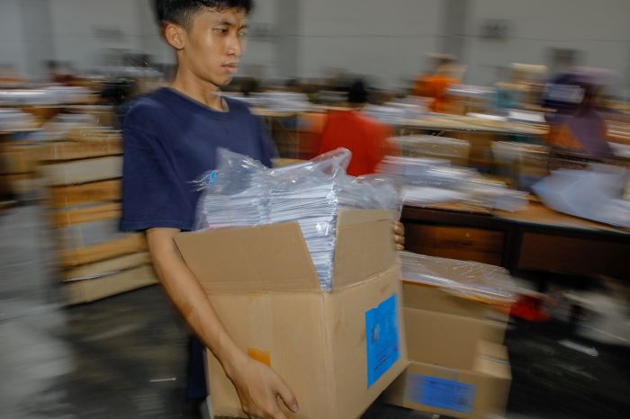 ANGKUT: Pekerja mengangkat surat suara Pemilu 2024 di gudang penyimpanan KPU Surabaya di kawasan Margomulyo, Surabaya. (SURYANTO/RADAR SURABAYA)