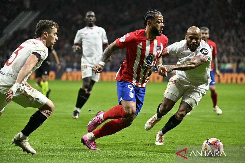 Penyerang Atletico Madrid Memphis Depay (tengah) berduel dengan bek Sevilla Marcao (kanan) pada pertandingan perempat final Piala Raja, di Stadion Metropolitano, Madrid, Kamis (25/1)